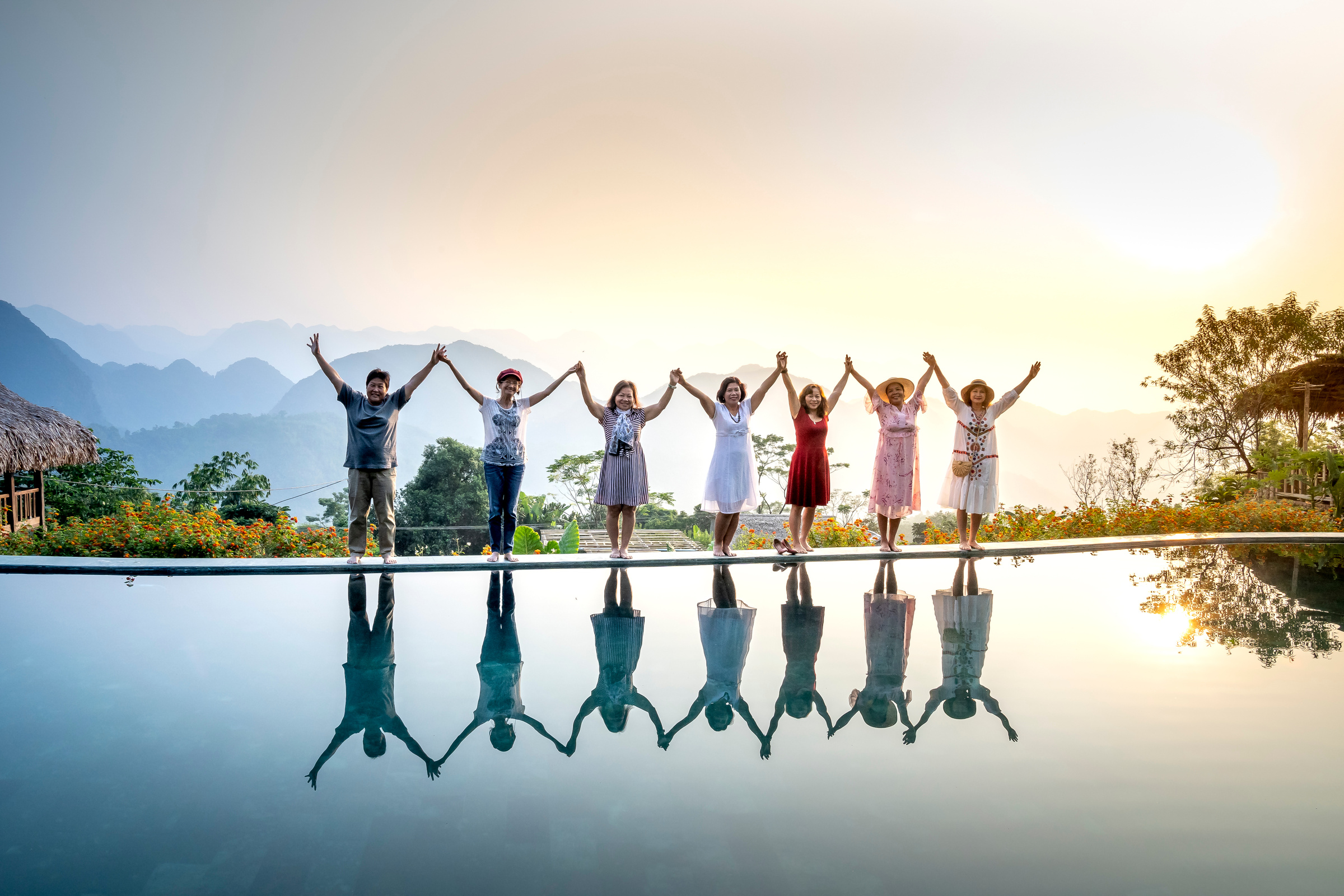 Happy women with arms raised at tropical pond